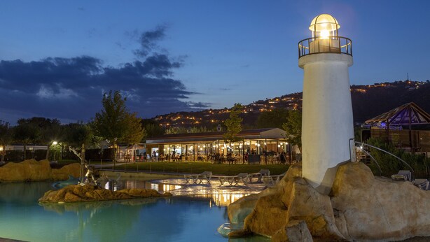 Un faro blanco, una piscina y un edificio con terraza.