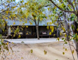 A rustic cabin with a covered porch and a dirt path leading to it.
