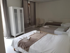 A hotel room with a large bed, a smaller bed, a wardrobe, and a chair. - Hôtel Notre Dame (Clery-Saint-Andre)