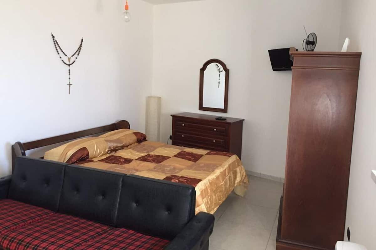 Un dormitorio con cama, cómoda, espejo y armario.