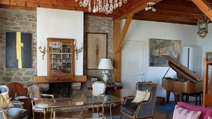 A cozy living room with a fireplace, a piano, and a bookshelf. - charming villa, exceptional sea view, with tuned piano, 6-8 people. (Saint-Nazaire)