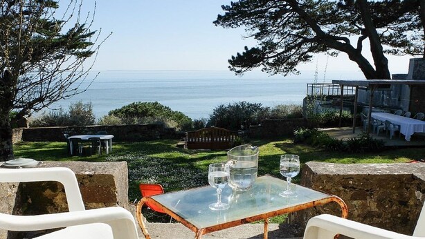 A table with two chairs and a glass of water, overlooking a scenic view of the sea. - charming villa, exceptional sea view, with tuned piano, 6-8 people. (Saint-Nazaire)