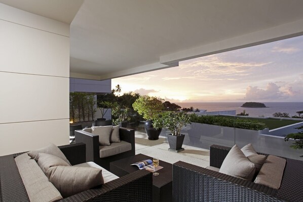 A modern outdoor seating area with wicker furniture and potted plants, overlooking a scenic ocean view at sunset. - The heights B18 Seaview near Kata Beach (Karon)