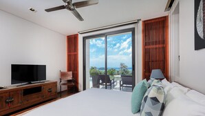 A bedroom with a large bed, a TV on a wooden cabinet, a ceiling fan, and a balcony with a view of the ocean. -  The Heights Kata Seaview C1 near Kata Beach (Karon)