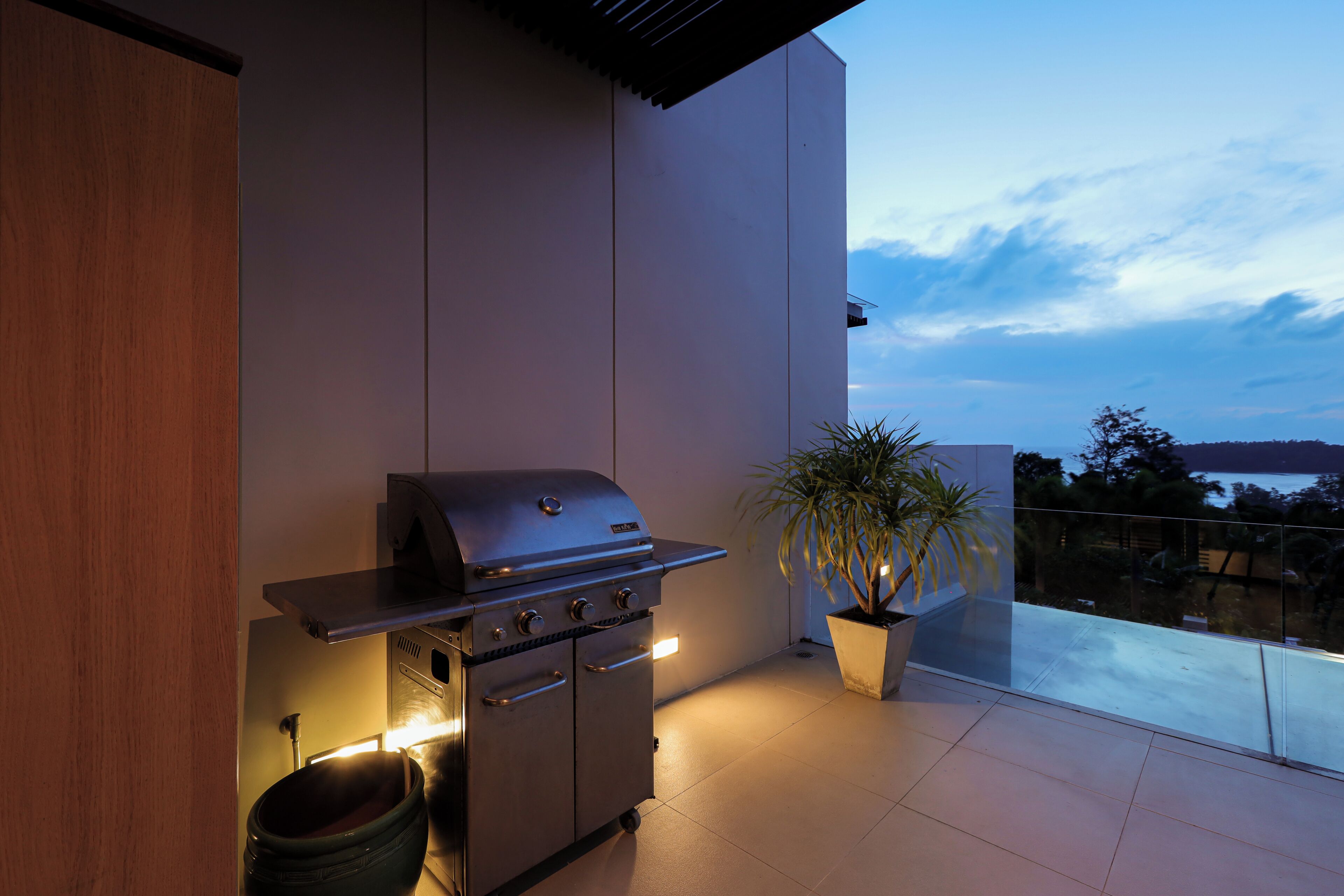 Eine Außenküche mit Grill, einem Blumentopf und Blick zum Himmel.