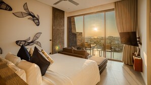 A modern hotel room with a large bed, a ceiling fan, a TV, and a balcony with a city view. - Villa Momo Private Pool near Kata Beach (Karon)