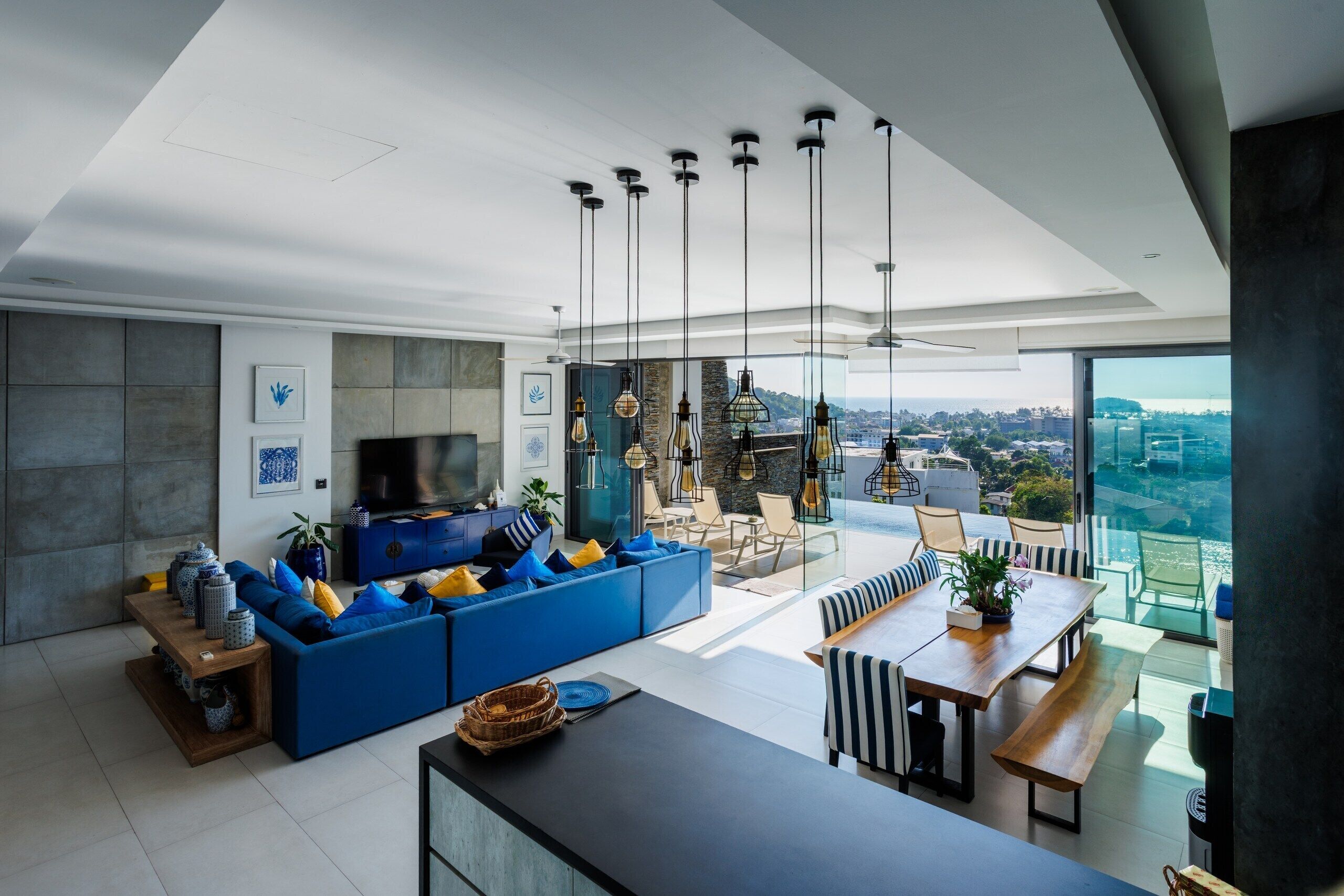 Ein modernes Wohnzimmer mit einem blauen Sofa, einem Esstisch und Blick auf die Stadt.