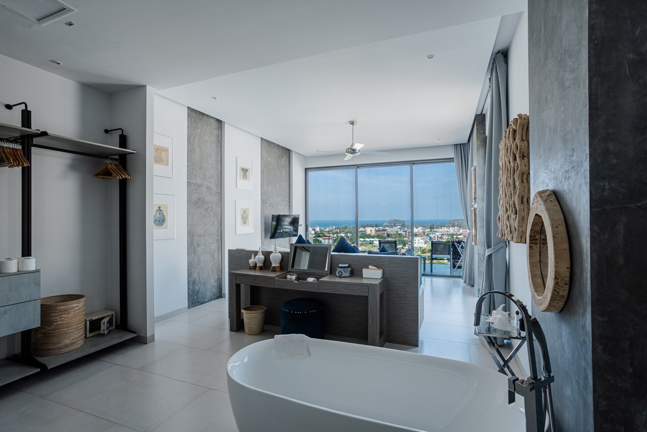 A modern bathroom with a freestanding bathtub, a vanity with a mirror, and a large window offering a city view.