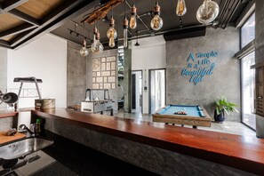 A modern bar area with a pool table, a foosball table, and a wall with a motivational quote. - Villa Momo Private Pool near Kata Beach (Karon)