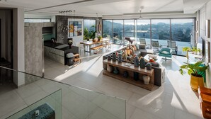 A spacious living area with a dining table, seating, and a view of the city. - Villa Omari Luxury Seaview Pool & Game Room (Karon)