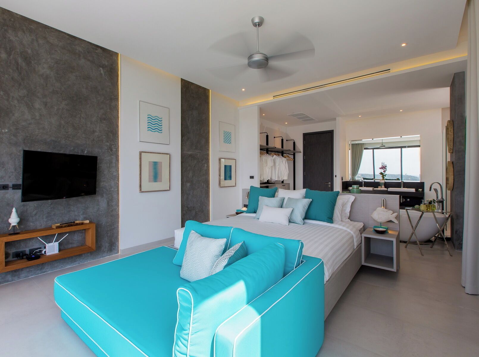 A modern bedroom with a large bed, a sofa, a TV, and a bathroom with a shower and sink.