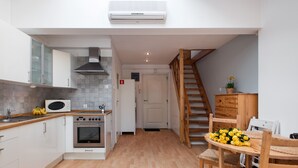 Una cucina moderna con mobili bianchi, un forno a microonde, un piano cottura e un tavolo da pranzo in legno con sedie.