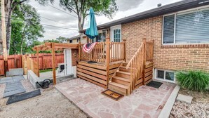 A backyard with a wooden deck, a small patio area, and a brick house. - 1 Br70's Inspired Comfy Condoclose to Broadmoor (Colorado Springs)