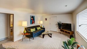 A living room with a sofa, coffee table, TV, and lamps. - 1 Br70's Inspired Comfy Condoclose to Broadmoor (Colorado Springs)