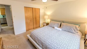 A bedroom with a bed, a ceiling fan, a nightstand, and a wooden wardrobe. - 1 Br70's Inspired Comfy Condoclose to Broadmoor (Colorado Springs)