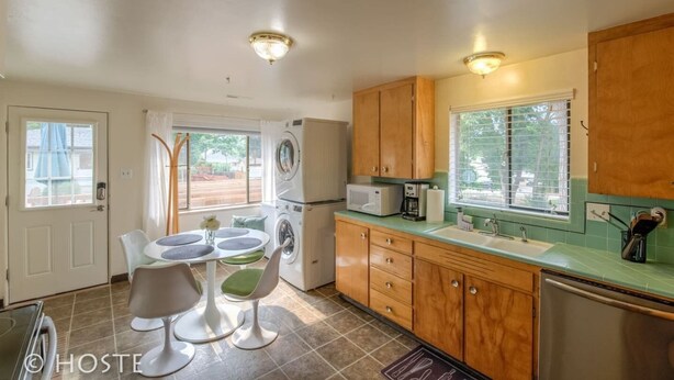 A compact kitchen with a dining area, a washing machine, a microwave, and wooden cabinets. - 1 Br70's Inspired Comfy Condoclose to Broadmoor (Colorado Springs)