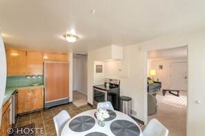 A compact kitchen with wooden cabinets, a stove, and a dining area with a table and chairs.