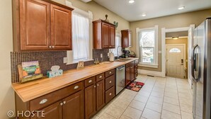 A kitchen with wooden cabinets, a tiled backsplash, and a stainless steel refrigerator. - 3 BR Beautifully Restored 1890`s Homedowntown (Colorado Springs)