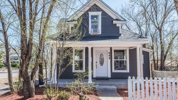 A two-story house with a dark exterior, a white front door, and a small porch area. - 3 BR Beautifully Restored 1890`s Homedowntown (Colorado Springs)
