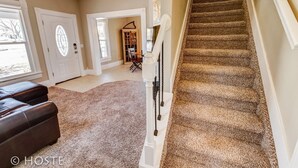 A home interior with a staircase, a living room with a brown leather sofa, and a carpeted floor. - 3 BR Beautifully Restored 1890`s Homedowntown (Colorado Springs)