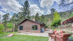 Un chalet rustique doté d’une grande fenêtre, d’un espace extérieur aménagé avec des sièges et d’une table de pique-nique.