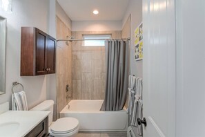 Une salle de bain moderne équipée d’une baignoire, de toilettes et d’un meuble-lavabo.