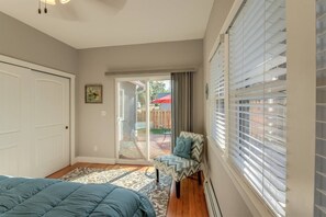 A bedroom with a bed, a chair, a sliding glass door leading to a patio, and a window with blinds.