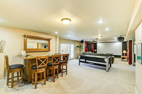 A room with a pool table, bar area with stools, a refrigerator, and a projector screen. - 5BR Mtn Views Family Getaway HOT TUB (Colorado Springs)