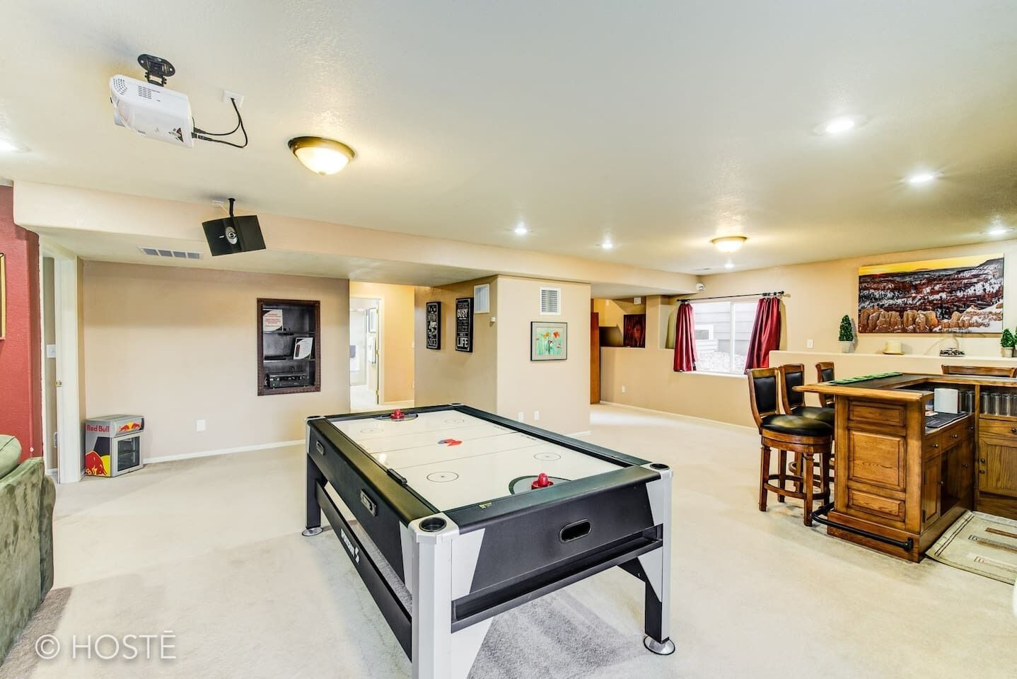 A spacious room with a pool table, a projector, and a dining area with chairs and a table.