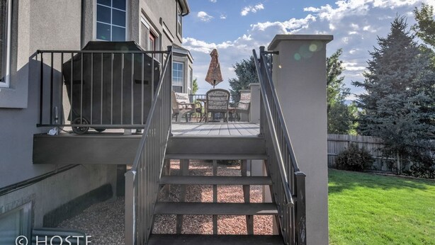 A house with a covered patio, a staircase leading to a deck, and a fenced yard.