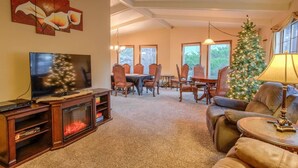 A living room with a fireplace, a television, a Christmas tree, and a dining area with chairs and a table. - 4BR Entertainer AF Academy Hot Tub, Firepit! (Colorado Springs)