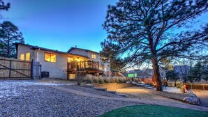 A modern house with a covered patio, a stone driveway, and a well-maintained lawn. - 4BR Entertainer AF Academy Hot Tub, Firepit! (Colorado Springs)