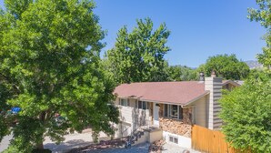 A house with a stone foundation, a red roof, and a wooden fence. - 4BR Dog Friendlygarden of the Godsbbq Grill! (Colorado Springs)