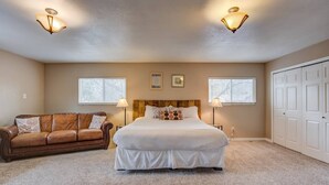 A bedroom with a large bed, two bedside lamps, a brown leather couch, and a closet. - 4BR Dog Friendlygarden of the Godsbbq Grill! (Colorado Springs)