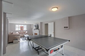 A room with a ping pong table, a sofa, a TV, and a fireplace. - 4 Bedroom Mountain View with Firepit & Ping Pong (Colorado Springs)