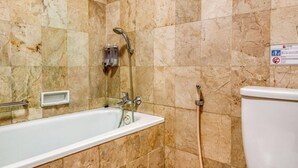 A bathroom with a bathtub, a shower, and a toilet. - Reddoorz Plus Near Dharmawangsa Square (Jakarta)
