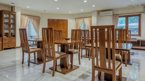 A spacious dining area with wooden furniture and a large window. - Reddoorz Plus Near Dharmawangsa Square (Jakarta)