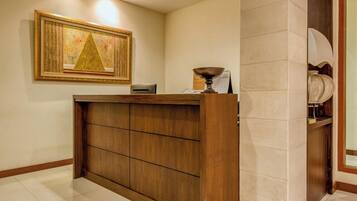 A reception desk with a wooden finish, a framed artwork above it, and a wall-mounted calendar.