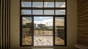 A room with a large sliding glass door leading to an outdoor terrace with a tiled floor and a view of buildings and a clear sky. - Yilan Siao Jhu (Jiaoxi)