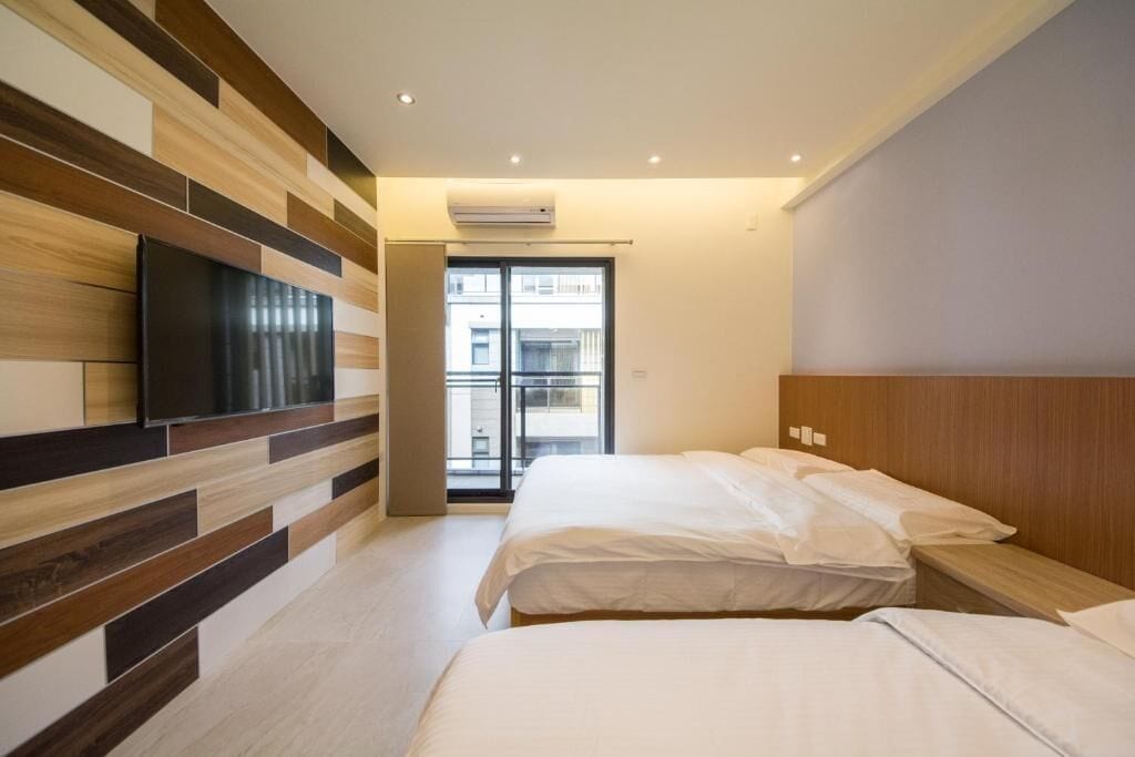 Een hotelkamer met twee bedden, een wandgemonteerde flatscreen televisie en een groot raam met uitzicht.