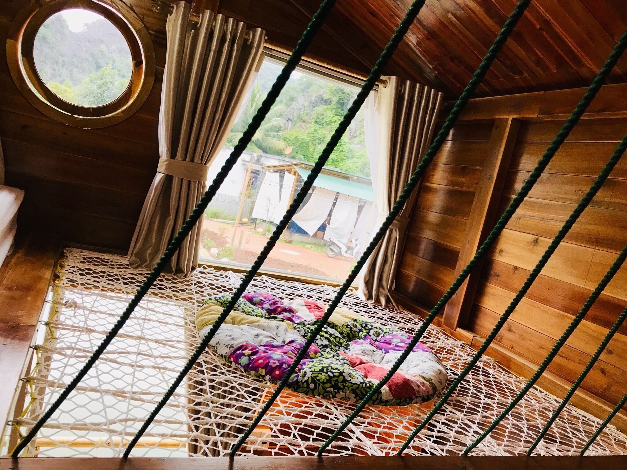 Une pièce chaleureuse avec un lit-hamac, des murs en bois et une vue sur l’extérieur.