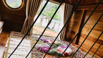 A cozy room with a hammock bed, wooden walls, and a view of the outdoors.