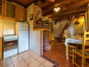 A kitchen with a gas stove, a refrigerator, and a brick oven. There is a dining table with chairs and a chandelier. - House Adrijana (Bribir)
