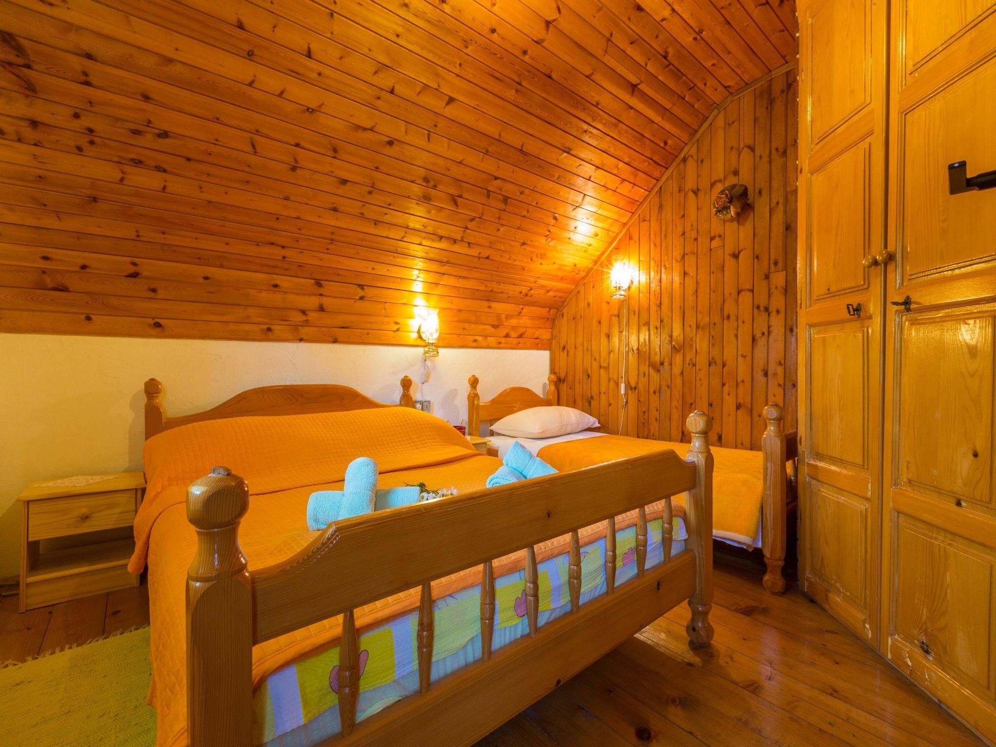 Een kamer met houten lambrisering, een bed, een nachtkastje en een kledingkast.