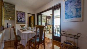 A dining area with a wooden table set for four, chairs, a chandelier, and a painting on the wall. - House Villa Vaho (Novi Vinodolski)