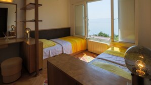 A bedroom with two beds, a wooden desk, a mirror, and a view of the sea. - House Villa Vaho (Novi Vinodolski)