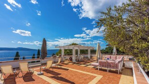 A terrace with outdoor seating, a pergola, and a view of the sea. - House Villa Vaho (Novi Vinodolski)