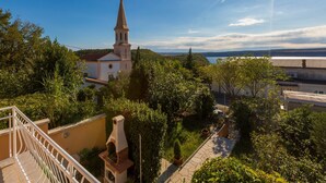 A church with a tall steeple, surrounded by lush greenery and a clear sky. - House Lara (Jadranovo)