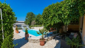 A pool area with stone flooring, potted plants, and outdoor furniture. - House Lara (Jadranovo)