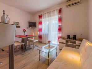 Ein modernes Wohnzimmer mit einem Glastisch, einem weißen Sofa und einem Essbereich mit Tisch und Stühlen.